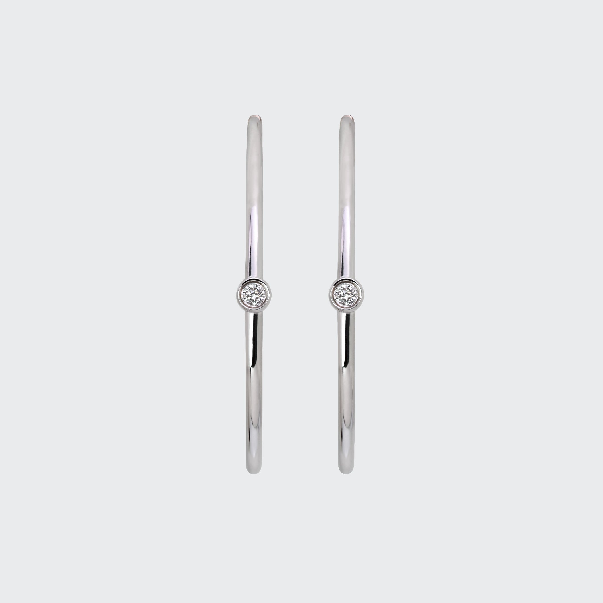 A pair of minimalist Odyssey Silver Hoops, each featuring a single bezel-set diamond on the front-facing side.