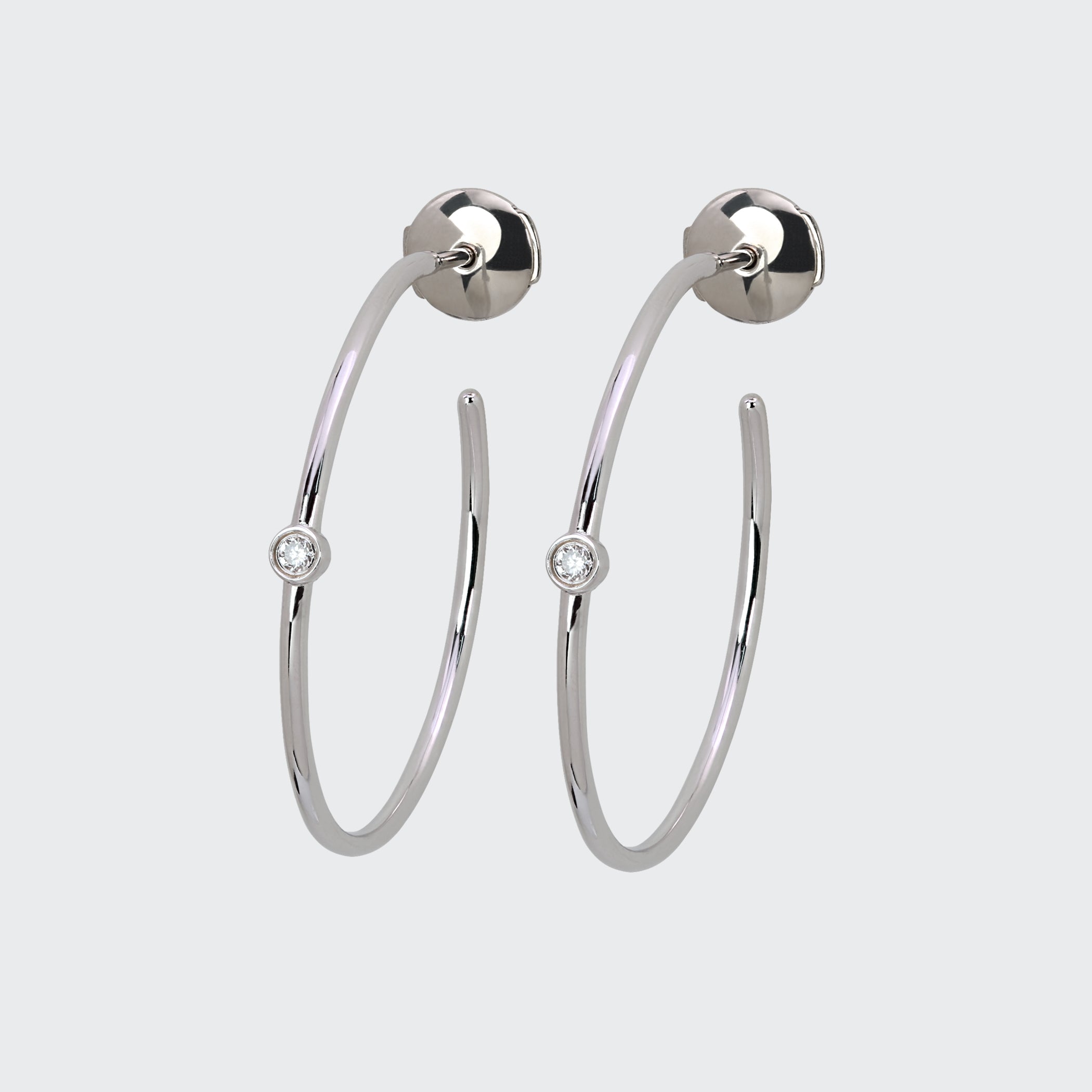 A pair of Lark & Berry Odyssey Silver Hoops in a minimalist style, each featuring a single bezel-set diamond accent.