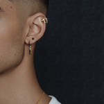 Close-up on a model's ear wearing the gold Palm Diamond Ear Cuff on the helix, styled with other earrings.