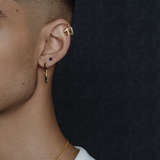 Close-up on a model's ear wearing the gold Palm Diamond Ear Cuff on the helix, styled with other earrings.
